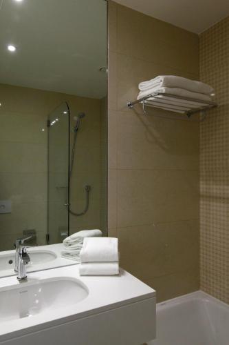 a bathroom with a sink and a shower with towels at Hotel Lis Baixa in Lisbon