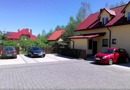 three cars parked in a parking lot next to a house at Agroturystyka Źródełko in Święta Katarzyna