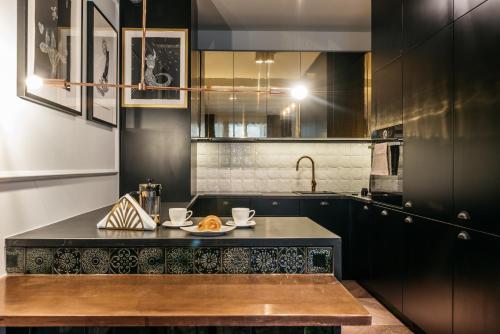 a kitchen with black cabinets and a black counter top at Harmonica Apartment by LoftAffair in Krakow
