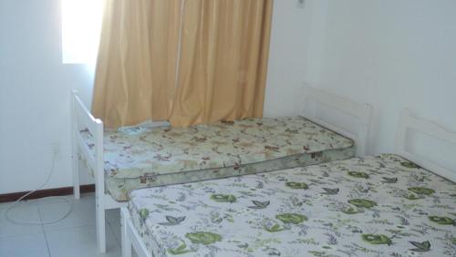 a small bedroom with two beds and a window at AP IVONETE -Victoria Residense in Governador Celso Ramos