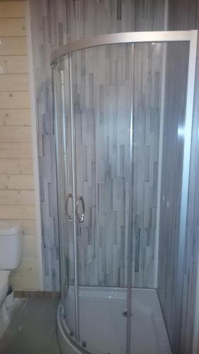 a shower with a glass door in a bathroom at Domek nad jeziorem Kątno Mazury in Kątno