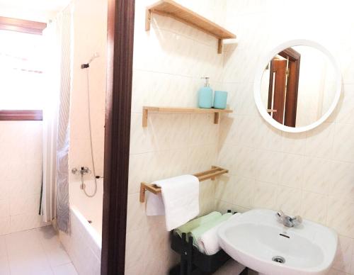 La salle de bains blanche est pourvue d'un lavabo et d'un miroir. dans l'établissement Centrico Y Acogedor, à Comillas