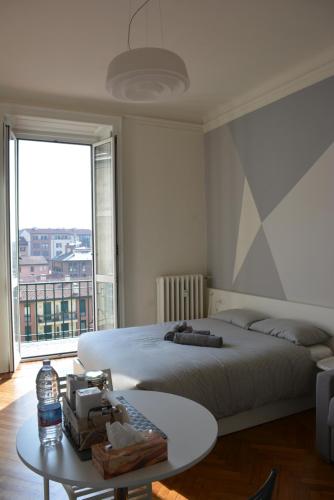 um quarto com uma cama, uma mesa e uma janela em Aria di Casa - Navigli Darsena em Milão