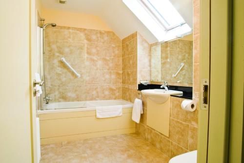 a bathroom with a bath tub and a sink at Ring of Kerry Holiday Cottages No 22 by Trident Holiday Homes in Kenmare