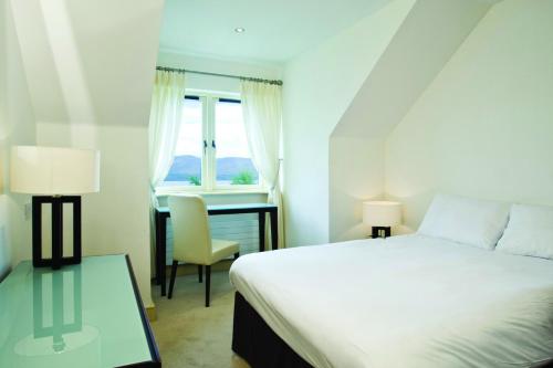 a bedroom with a bed and a desk and a window at Ring of Kerry Holiday Cottages No 22 by Trident Holiday Homes in Kenmare