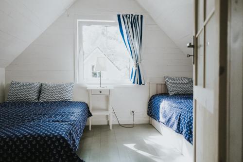 two beds in a small room with a window at Marynarskie Domki in Pobierowo