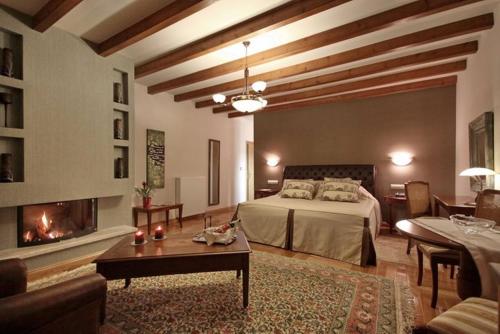 a bedroom with a bed and a living room with a fireplace at Methexis Boutique Hotel in Dhimitsana