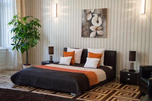 a bedroom with a large bed with orange and white pillows at Harmonia Palace in Budapest