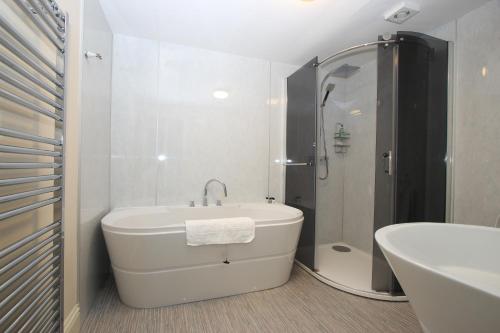 a white bathroom with a tub and a sink at Caledonian House in Portmahomack