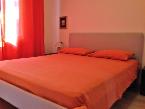 a bedroom with a bed with orange sheets and a window at casa caberlon in Malcesine