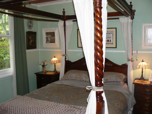 a bedroom with a four poster bed and two lamps at Lemon Tree Cottage in Leura