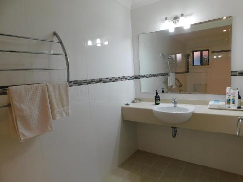 Baño blanco con lavabo y espejo en Beachport Bed & Breakfast, en Port Macquarie