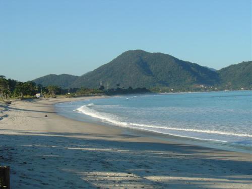 a beach with the ocean and mountains in the background at Solar do Forte Flats in Ubatuba