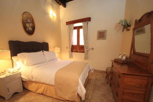 a bedroom with a bed and a dresser and a mirror at Hotel Boutique Ponciano in Guanajuato