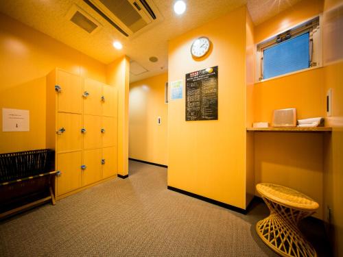 a room with yellow walls and a clock on the wall at Natural Hot Spring Super Hotel Tottori Eki Kitaguchi in Tottori