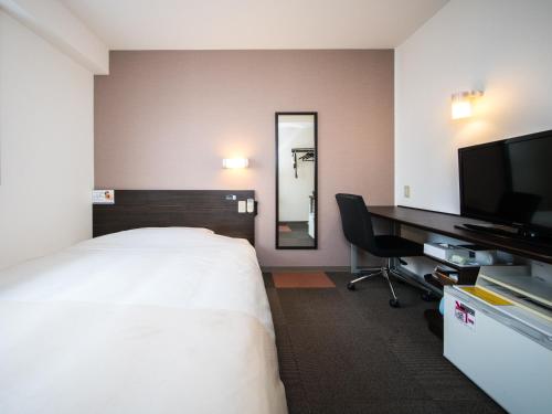 a hotel room with a bed and a desk and a television at Natural Hot Spring Super Hotel Tottori Eki Kitaguchi in Tottori