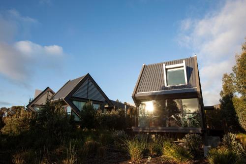 a house with a metal roof on top of a field at MONA Pavilions in Hobart