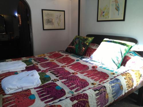 a bed with a quilt on it in a room at Samira's Birds & Butterflies Park-Spashram Ganga Beach Retreat in Rishīkesh