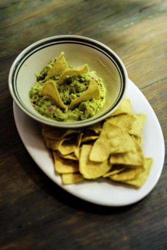 a plate of food with a bowl of guacamole and chips at Hotel Casa Perico in Rio Dulce