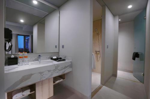 a bathroom with a sink and a large mirror at Harper Cikarang by ASTON in Cikarang