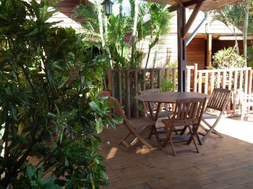 Une table et des chaises en bois sont disponibles sur la terrasse. dans l'établissement Le Cardinal des Grands Bleus, à Saint-Leu