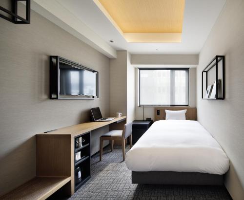 a hotel room with a bed and a desk with a computer at LAMP LIGHT BOOKS HOTEL nagoya in Nagoya