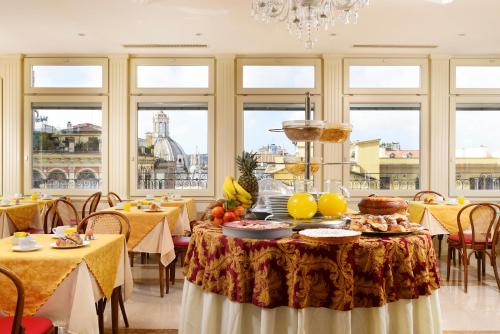 una sala da pranzo con tavolo e cibo di Hotel Bolivar a Roma