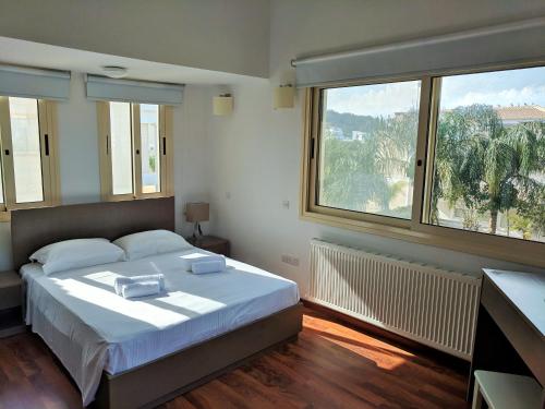 a bedroom with a large bed and two windows at ANTHORINA VILLA 9 in Protaras