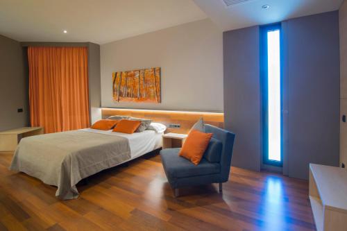a bedroom with a bed and a blue chair at Hotel America Igualada in Igualada