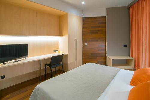 a bedroom with a bed and a desk with a television at Hotel America Igualada in Igualada