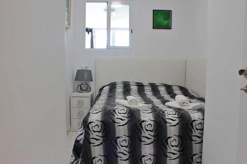 1 dormitorio con 1 cama con edredón blanco y negro en Apartamento Horizonte, en Calpe