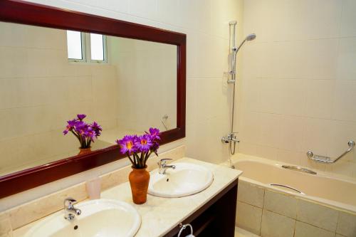 a bathroom with two sinks and a mirror with purple flowers at Waterside Bentota in Bentota