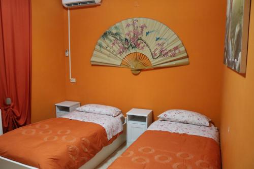 two beds in a room with an orange wall at Le Sirene Bed and Breakfast in Cellamare