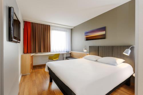 a hotel room with a large white bed and a window at ibis Hotel Frankfurt Messe West in Frankfurt/Main