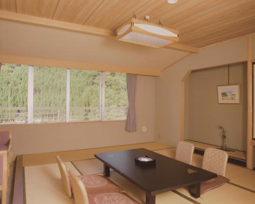 a living room with a table and chairs and windows at Hotel Yunojin in Minakami