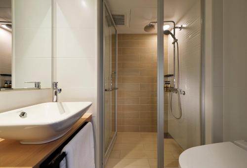 a bathroom with a sink and a shower at LAMP LIGHT BOOKS HOTEL nagoya in Nagoya