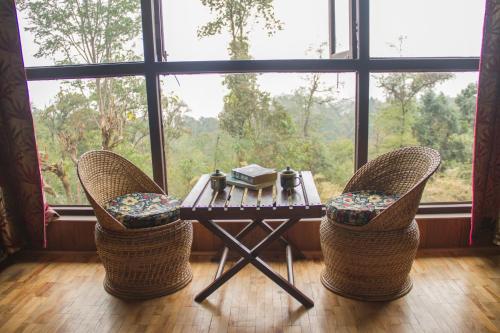 mesa y sillas en una habitación con ventana grande en The Barfung Retreat en Gangtok