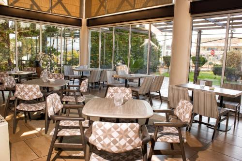 un restaurante con mesas, sillas y ventanas en Agrinio Imperial Hotel, en Agrinio