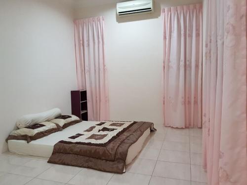 a bedroom with a bed and pink curtains at Big Garden Homestay in Pantai Remis