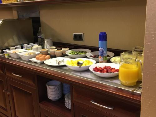 a buffet with bowls of food and orange juice at Hotel Campoamor in Oviedo