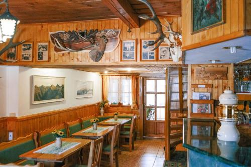 un restaurante con paredes de madera, mesas y sillas en Penzión Hubert en Zuberec