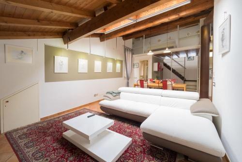 a living room with white furniture and a red rug at Alkimia Apartments in Ferrara