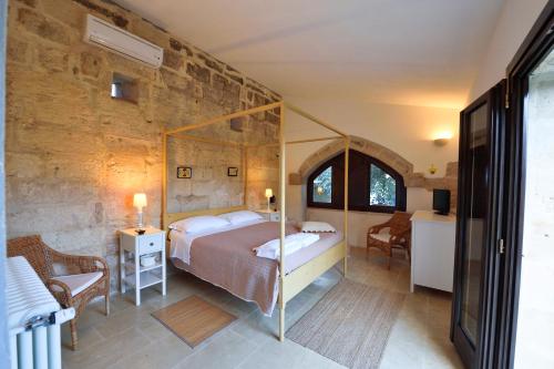 1 dormitorio con cama y pared de piedra en Masseria Lacco, en Muro Leccese