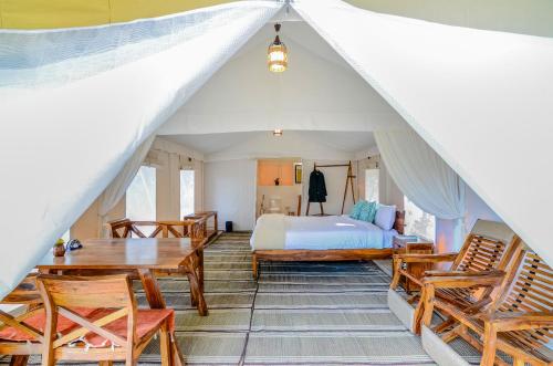 a bedroom with a bed and a table and chairs at Nayalap - Rural Himalayan Glamping in Shitlakhet