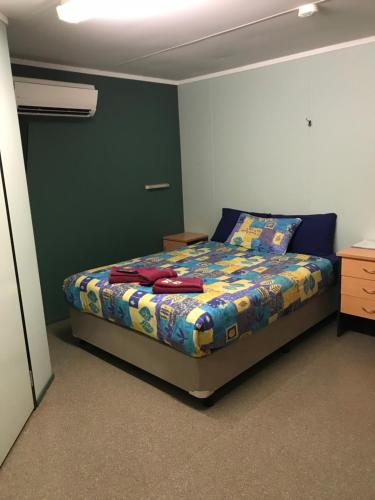 1 dormitorio con 1 cama con un edredón colorido en Karratha Lodge TWA en Karratha