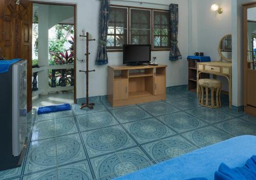 a bedroom with a tv and a tiled floor at Gila's Garden in Lamai