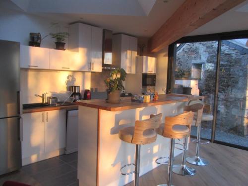 a kitchen with white cabinets and a counter with stools at La Petite Charnasserie in Angers