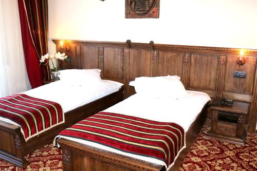 two beds in a room with wood paneling at Castel Transilvania in Baia Mare