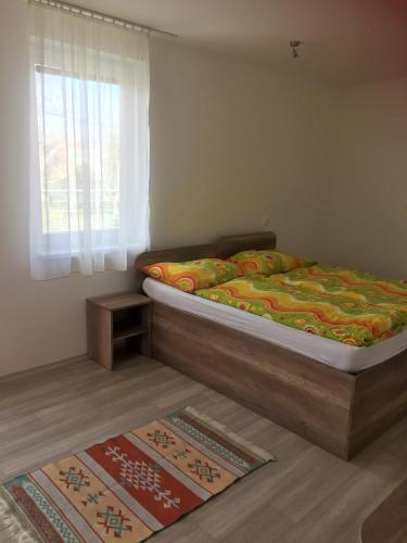 a bedroom with a bed and a window and two rugs at Promenád apartmány in Veľký Meder