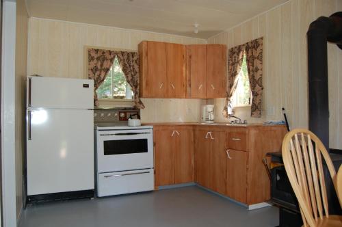 uma cozinha com um frigorífico branco e armários de madeira em Rivière Petit Saguenay em Petit-Saguenay